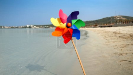 Foto de Colorido molinete girando en el viento en una playa de arena, evocando los conceptos de viaje, vacaciones de verano, vacaciones, turismo de playa y alegría - Imagen libre de derechos