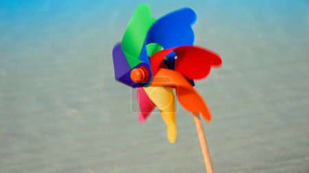 Photo for Vibrant pinwheel twirls on a sandy beach, evoking the carefree spirit of summer vacation, travel, and childhood wonder - Royalty Free Image