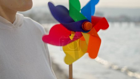Foto de Mujer en vacaciones de verano, disfrutando de la playa de arena marina, sosteniendo un colorido volante giratorio y capturando las emociones positivas - Imagen libre de derechos