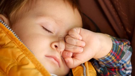 Foto de Primer plano de la cara del bebé dormido acostado en el cochecito en el parque. Desarrollo infantil, niños descansando, cuidado de la salud del bebé. - Imagen libre de derechos
