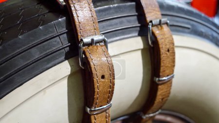 Foto de Primer plano de cinturones de cuero que sostienen el neumático de rueda de repuesto en el viejo coche vintage. - Imagen libre de derechos
