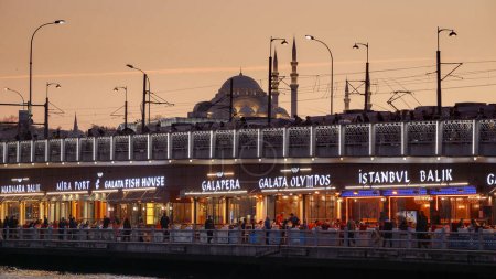 Téléchargez les photos : 15 mars 2023, Turquie, Istanbul. Pêcheur et restaurants sur le célèbre pont de Galata au coucher du soleil. - en image libre de droit