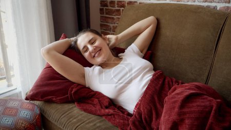 Photo for Happy smiling woman waking up on sofa after having a day dream and stretching out hands. - Royalty Free Image