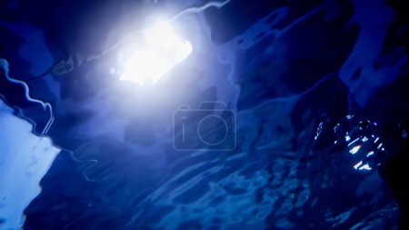 Foto de Vista desde el fondo de la piscina sobre la luz que brilla a través del agua y las ondas. Fondo submarino abstracto o telón de fondo - Imagen libre de derechos