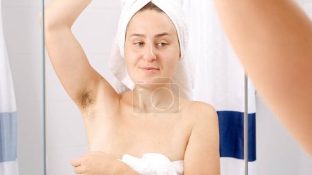 Photo for Happy smiling woman in white bath towel touching her growing hair under arms. Concept of beautiful female, natural beauty, feminity and body hair - Royalty Free Image