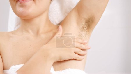 Photo for Closeup of long dark hair growing under arms of young woman standing at bathroom mirror. Concept of beautiful female, natural beauty, feminity and body hair - Royalty Free Image