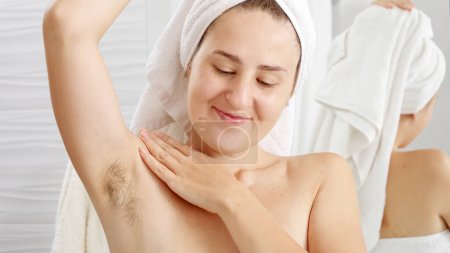 Photo for Portrait of smiling natural woman with growing armpit hair posing in bathroom. Concept of hygiene, natural beauty, feminity and body hair growth - Royalty Free Image