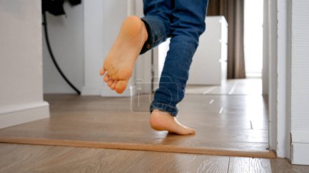 Photo for Little boy running down a long wooden corridor at home. Concept of a happy childhood, playful activities at home, and the development of a child's motor skills - Royalty Free Image
