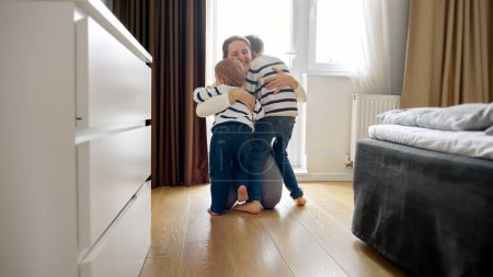Photo for Two little boy's running to loving mother at home. Concept of a happy childhood, playing indoors, and the growth and development of a child's physical and motor skills - Royalty Free Image