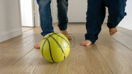 Foto de Dos niños felices pueden ser vistos jugando un partido de fútbol en un piso de madera en un pasillo de la casa. La cámara lenta captura la alegría y el entusiasmo, jugando y divirtiéndose - Imagen libre de derechos