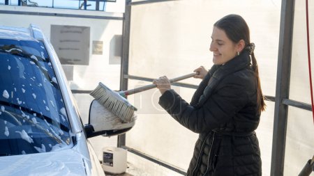 Téléchargez les photos : Belle femme qui lave sa voiture au lave-auto libre service. Entretien automobile, nettoyage des transports, voiture sale - en image libre de droit