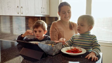 Téléchargez les photos : Bonne famille avec des enfants qui mangent de la soupe pour le dîner sur la cuisine. Nourriture domestique, cuisine à la maison, alimentation saine des enfants - en image libre de droit