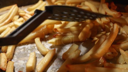 Photo for Closeup of stirring frying french fries potato on baking tray in oven. Cooking at home or restaurant. Fast food, unhealthy nutrition. - Royalty Free Image