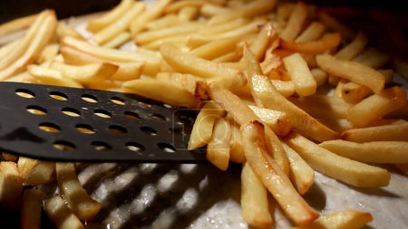 Photo for Closeup of stirring baking french fries in oven with spatula. Fast food, healthy nutrition, cooking in oven - Royalty Free Image
