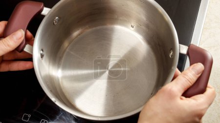 Foto de Primer plano de poner agua fría en olla en estufa de cocción por inducción - Imagen libre de derechos