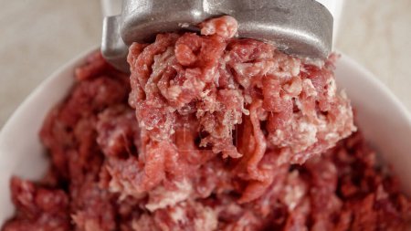 Photo for Closeup of minced meat coming out of electric grinder and falling in bowl. Cooking at home, kitchen appliance, healthy nutrition, hamburger ingredients - Royalty Free Image