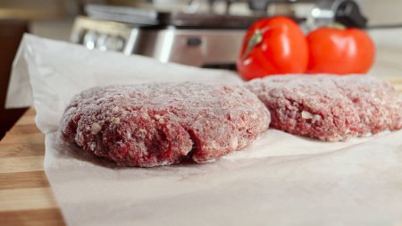 Foto de Hamburguesa congelada empanadas e ingredientes que se encuentran en la mesa de la cocina junto a la parrilla eléctrica - Imagen libre de derechos