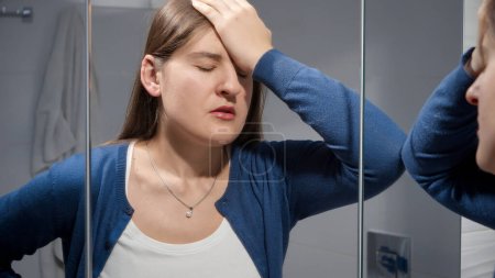 Photo for Upset woman suffering from problems in life leaning on mirror in bathroom. Concept of depression, stress, mental illness and problems, loneliness and frustration - Royalty Free Image