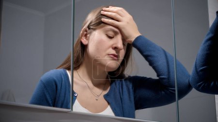Foto de Retrato de mujer molesta apoyada en el espejo del baño y suspirando. Concepto de depresión, estrés, enfermedad mental y problemas, soledad y frustración - Imagen libre de derechos