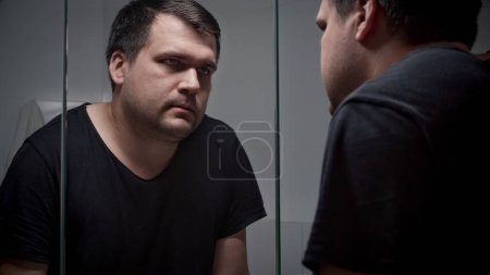 Photo for Upset man leaning on sink and looking in mirror at bathroom. Concept of depression, suicide, stress, mental illness, loneliness and frustration - Royalty Free Image