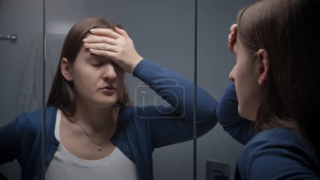 Téléchargez les photos : Femme stressée bouleversée regardant son reflet dans le miroir de salle de bains. Dépression féminine et émotions négatives. - en image libre de droit