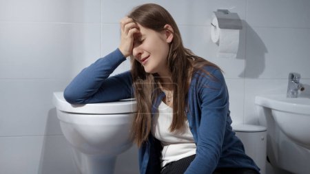 Photo for Crying young woman having problems and stress in life sitting on floor in toilet. Concept of depression, suicide, stress, mental illness, loneliness and frustration - Royalty Free Image