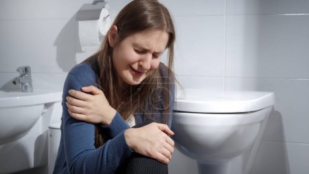 Photo for Lonely woman suffering from domestic violence crying on floor in toilet. Concept of depression, home violence, suicide, stress, loneliness and frustration - Royalty Free Image