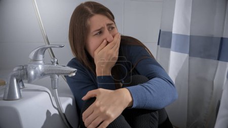 Téléchargez les photos : Femme effrayée se cachant dans la salle de bain du criminel et fermant sa bouche avec la main. Concept de violence domestique victime, stress, danger à la maison, peur. - en image libre de droit