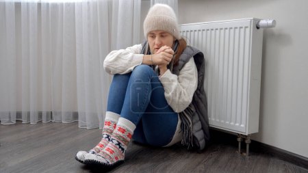 Femme bouleversée essayant de se réchauffer dans un appartement froid sans chauffage. Concept de crise énergétique, factures élevées, système de chauffage cassé, économie et économies sur les paiements mensuels des services publics