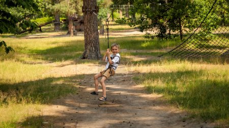 Foto de Niño divirtiéndose mientras monta en tirolina en el parque de aventuras. Infancia activa, estilo de vida saludable, niños jugando al aire libre, niños en la naturaleza - Imagen libre de derechos