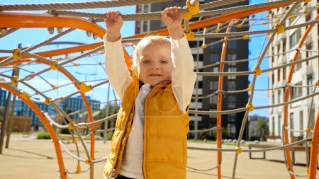 Photo for Cute baby boy hanging on rope at playground. Children playing outdoor, kids outside, summer holiday and vacation - Royalty Free Image
