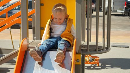 Photo for Little baby boy sitting on the top of the slide at playground and asking for help. Happy parenting, family having time together, kids and parents outdoors - Royalty Free Image