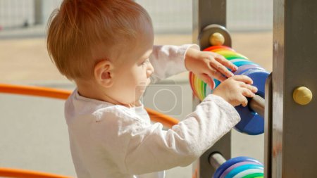 Téléchargez les photos : Petit garçon jouant sur une aire de jeux avec un boulier coloré. Développement des enfants, éducation des enfants, apprentissage des bébés - en image libre de droit