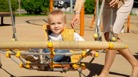 Photo for Cute baby boy swinging with mother in spider web swing on playground. Children playing outdoor, kids outside, summer holiday and vacation - Royalty Free Image