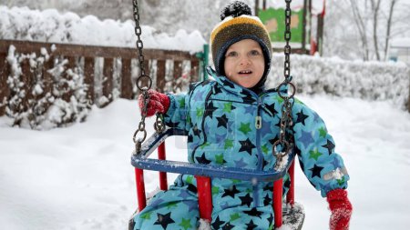 Foto de Retrato de un niño feliz disfrutando de un paseo en invierno en el parque, rodeado de árboles cubiertos de nieve y hermosos paisajes de invierno - Imagen libre de derechos