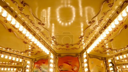 Téléchargez les photos : Carrousel décoré coloré avec beaucoup de lumières incandescentes tournant au parc d'attractions. - en image libre de droit