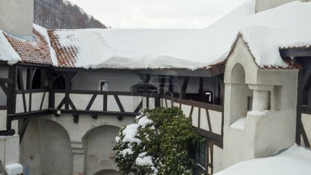 Foto de Largos pasillos y galerías bajo tejados cubiertos de nieve en el antiguo castillo medieval en invierno. - Imagen libre de derechos