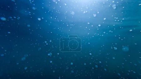 Photo for Underwater shot of sun rays shining through clear sea water with rising up air bubbles. - Royalty Free Image