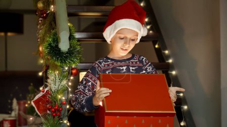 Photo for Portrait of happy smiling boys in Santa hat gets excited after opening magical gift or present box on Christmas eve. Family celebrations on winter holidays - Royalty Free Image