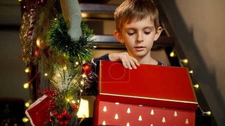 Téléchargez les photos : Petit garçon excité ouvre boîte cadeau de Noël avec cadeau du Père Noël et se fâche après avoir obtenu jouet qu'il ne souhaitait pas. - en image libre de droit