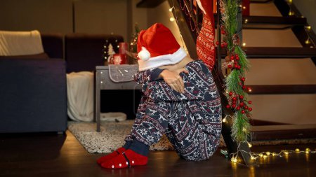 Photo for Little upset boy got sad and started crying while waiting for Santa on Christmas eve. Sadness, depression, solitude and negative emotions on winter holidays and New Year - Royalty Free Image