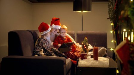 Foto de Familia feliz viendo películas en la noche de Navidad en la tableta en la sala de estar. Vacaciones de invierno, celebraciones y fiestas - Imagen libre de derechos