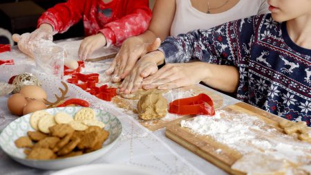 Foto de Primer plano de la madre enseñando a sus hijos cómo hacer galletas y pan de jengibre para Navidad en la cocina. Vacaciones de invierno, celebraciones y fiestas - Imagen libre de derechos