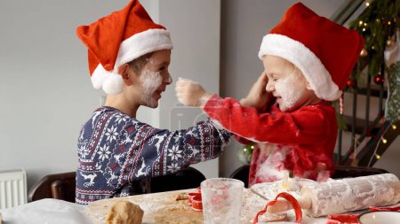 Photo for Two happy brothers getting messy in flour and playing while cooking cookies for Christmas. Winter holidays, celebrations and party - Royalty Free Image