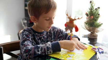 Téléchargez les photos : Portrait rapproché du petit garçon en pyjama écrivant une lettre au Père Noël le matin de Noël. - en image libre de droit