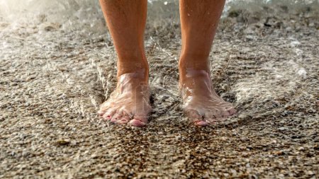 Téléchargez les photos : Gros plan d'eau de mer chaude qui coule entre les jambes des femmes debout sur une plage océanique. - en image libre de droit