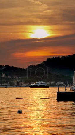 Téléchargez les photos : Image verticale du yacht sortant du port maritime au coucher du soleil. - en image libre de droit