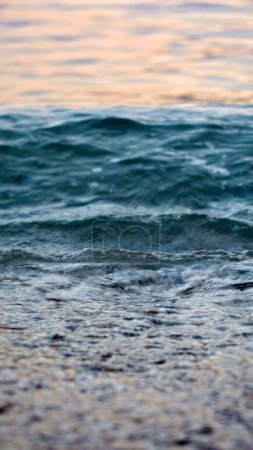Téléchargez les photos : Calme vagues de mer roulant sur la plage de l'océan au coucher du soleil. Vacances, vacances d'été et tourisme. - en image libre de droit