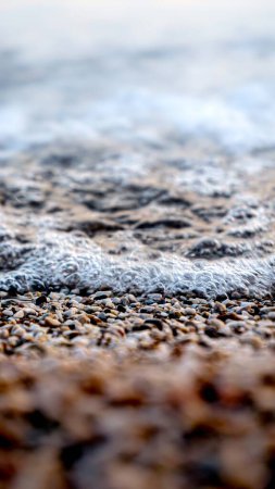 Téléchargez les photos : Plan macro abstrait de mousse, vagues de mer calmes et petits rochers sur une plage de mer. - en image libre de droit