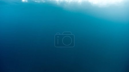 Abstract blurred underwater background of light rays shining through waves and clear sea water.